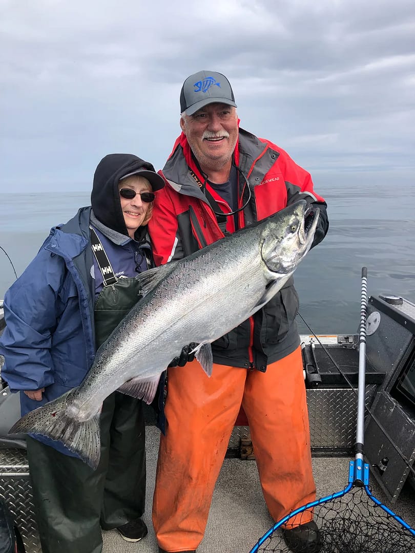 Terry Mulkey and client in boat holding up large salmon on the ocean