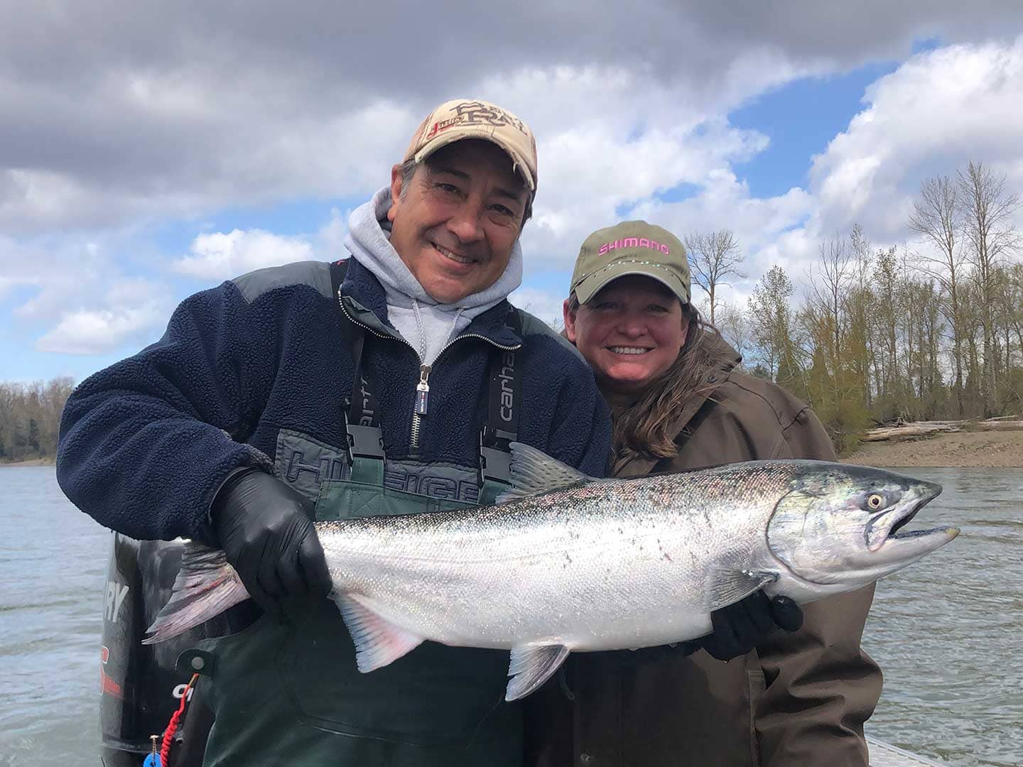 A man and a woman holding up a steelhead on a fishing boat