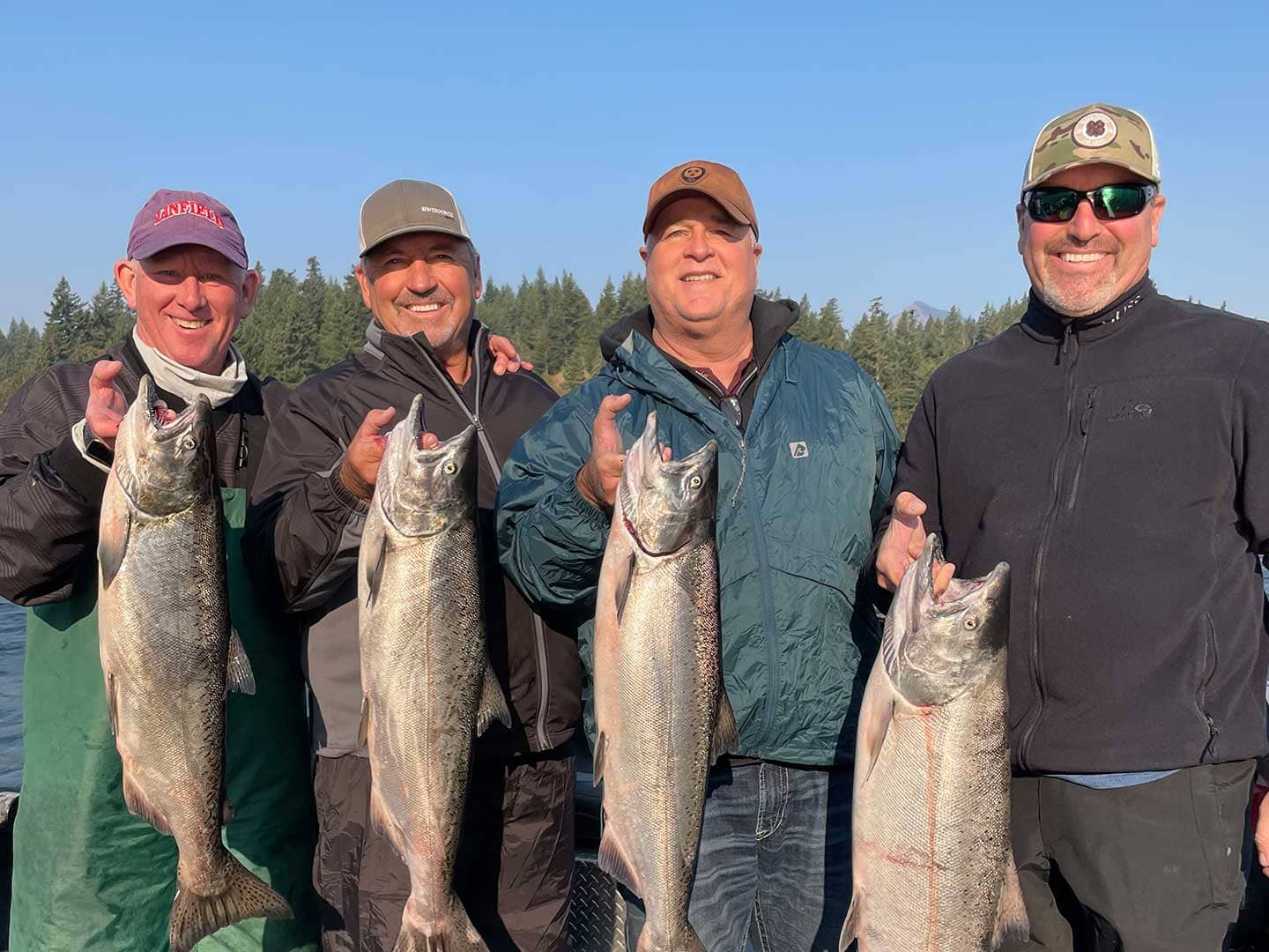 Group of four men each holding up a salmon